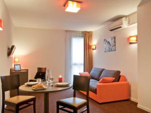 ein Wohnzimmer mit einem Sofa und einem Tisch in der Unterkunft Aparthotel Adagio Access Poitiers in Poitiers