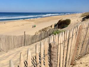 ein Holzzaun an einem Strand mit Blick auf das Meer in der Unterkunft Appartement Résidence Saint Jours - Centre ville in Vieux-Boucau-les-Bains + 2 Fotos