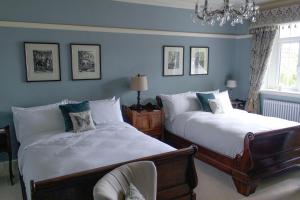 a bedroom with two beds and a chandelier at Gellihaf House in Blackwood