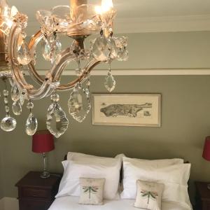 a chandelier hanging over a bed with white pillows at Gellihaf House in Blackwood