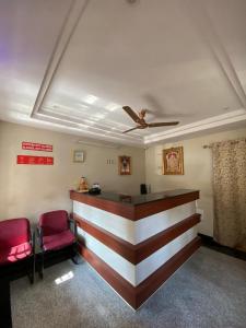 a bar in a waiting room with two red chairs at Hotel Renuka in Visakhapatnam