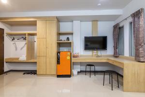Zimmer mit einem Schreibtisch, einem TV und einem Kühlschrank. in der Unterkunft The Rama Hotel in Chiang Rai