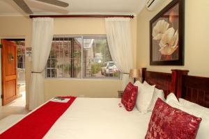 Un dormitorio con una cama con almohadas rojas y una ventana en Chartwell Guest House, en Durban