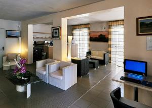 a living room with white chairs and a television at Bolgheri Marina Resort in Marina di Bibbona