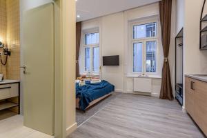 1 dormitorio con 1 cama y baño con ventanas en Gellért Budapest Suites, en Budapest