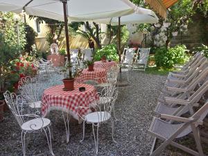 a patio with tables and chairs and an umbrella at Hotel Triestina in Noli