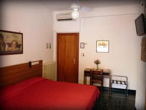 a bedroom with a red bed and a wooden door at Hotel Triestina in Noli