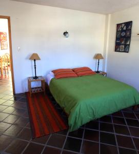 a bedroom with a bed with green sheets and two lamps at La Posada del Quinde in Otavalo