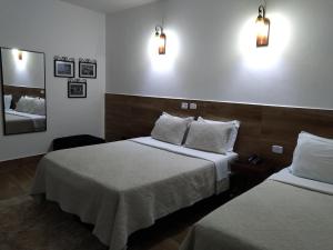 a hotel room with two beds and a mirror at Medieval Hotel in Três Corações