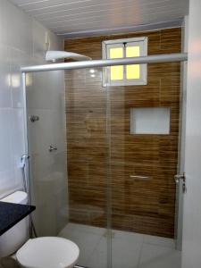 uma casa de banho com um chuveiro, um WC e uma janela. em Pousada Ilha do Meio em Itacimirim