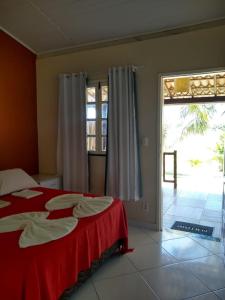 a bedroom with a red bed and a large window at Pousada Ilha do Meio in Itacimirim