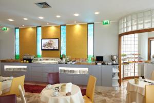 a restaurant with tables and chairs and a kitchen at Termini Beach Hotel & Suites in Lido di Jesolo
