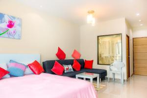 1 dormitorio con 1 cama y 1 sofá con almohadas rojas en The Nai Thon Condominium Unit en Nai Thon Beach