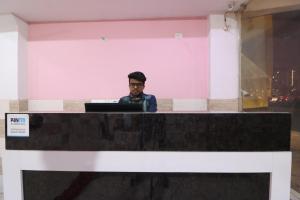 a man sitting at a desk with a laptop computer at Red rose hotel in Ghaziabad