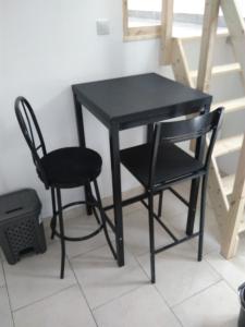 a black table and two chairs next to a staircase at jolie appartement centre de Fismes in Fismes