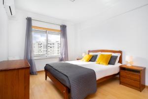 Un dormitorio con una cama con almohadas amarillas y una ventana en Lisboa, Cidade, Elegant Apartment with Air Cond, Free WIFI and Near Metro, by IG, en Lisboa