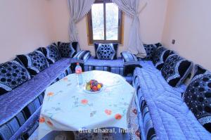 a room with blue couches and a table with a bowl of fruit at Gite Ghazal - Atlas Mountains Hotel in Imlil