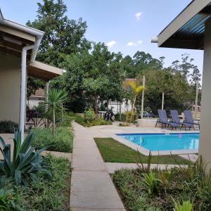 a swimming pool in a yard with chairs around it at Veki's Town Lodge in Mbabane