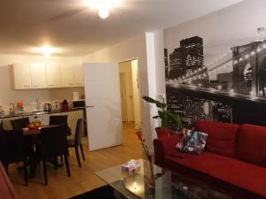 ein Wohnzimmer mit einem roten Sofa und einer Küche in der Unterkunft Grand F3 CONFORTABLE 5 mn de Paris et proche Disneyland in Maisons-Alfort