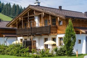 uma grande casa de madeira com um guarda-chuva em frente em Alpenchalets Flachauer Gutshof em Flachau