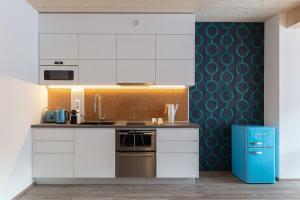 eine Küche mit weißen Schränken und einem blauen Kühlschrank in der Unterkunft ARTMUR Apartment in Sankt Georgen ob Murau