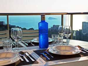a table with a blue bottle of wine and glasses at Benidorm HEAVEN 29th floor in Benidorm