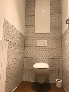a bathroom with a toilet and a white tiled wall at Augustodun'Home in Autun