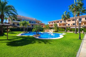 a resort yard with a swimming pool and palm trees at Jardines del Pla in Jávea