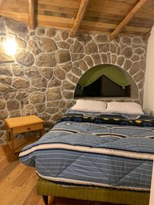 a bed in a room with a stone wall at Illa Wasi Sacred Valley in Urubamba