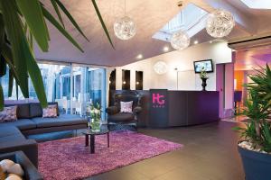 a lobby with a couch and a table and a tv at Hotel Du Golf in Saint-Étienne