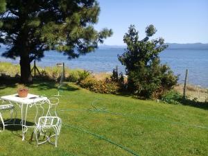 einen Tisch und Stühle im Gras in der Nähe des Wassers in der Unterkunft San Benito de Palermo in San Carlos de Bariloche