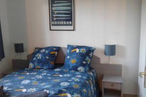 a bedroom with a bed with a blue comforter at T2 Antigua Ondres plage avec piscine et tennis in Ondres +23 photos