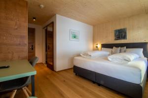 a bedroom with a large bed and a desk and a table at Wally Berg-Appartements in Zams