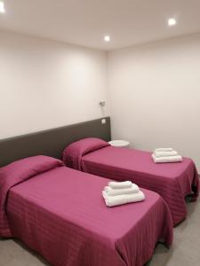 two beds in a room with pink sheets and towels at Vico Spina 5 in Milazzo