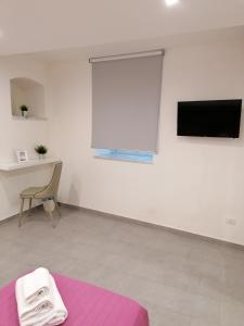biały pokój z telewizorem i fioletowym łóżkiem w obiekcie Vico Spina 5 w mieście Milazzo