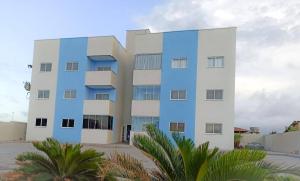 un edificio azul y blanco con palmeras delante en Aquaville Atalaia Apartamentos, en Luís Correia