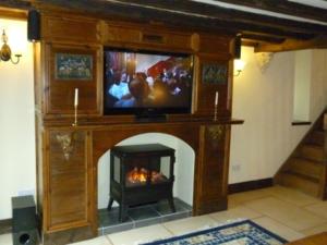 a living room with a fireplace with a tv above it at The Old Carthouse in Bridgwater