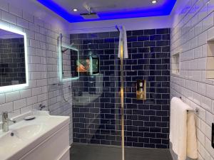 a blue tiled bathroom with a shower and a sink at The 25 Boutique B&B - Adults Only in Torquay