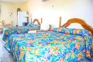 a bedroom with two beds with a colorful bedspread at Point Village Beach Studios in Negril