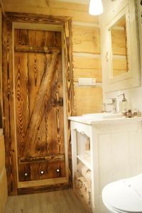a bathroom with a wooden door and a sink at Smolnikowe Klimaty - Chyżula in Komańcza