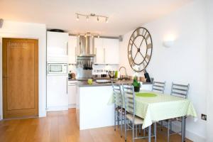 a kitchen with a table and chairs and a kitchen with white cabinets at Millendreath at Westcliff - Self Catering flat with amazing sea views in Looe