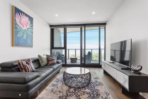 sala de estar con sofá y TV en Domi Serviced Apartments, en Glen Waverley