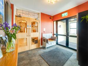 a lobby with orange walls and a vase of flowers at Standing Stones Lodge in Belfast