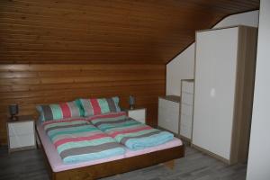 a bed with striped pillows in a room with wooden walls at Haus am Mühlberg in Fischbachtal