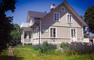 a gray house with a porch and a yard at Three Pheasants Boutique Bed and Breakfast in Ekeby