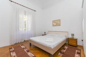 a white bedroom with a bed and a window at Veranda Rooms in Dubrovnik