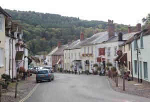 uma rua numa pequena cidade com casas e carros em Exmoor House em Dunster