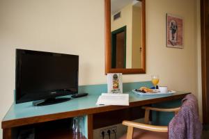 a room with a desk with a television and a plate of food at Hotel Jardín de Aranjuez in Aranjuez