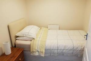 a bedroom with a bed with white sheets and pillows at Sister's Apartment in Llanelli