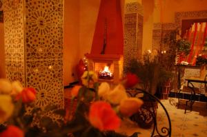 ein Wohnzimmer mit Kamin und Blumen davor in der Unterkunft Riad MAHJOUBA MARRAKECH & SPA in Marrakesch